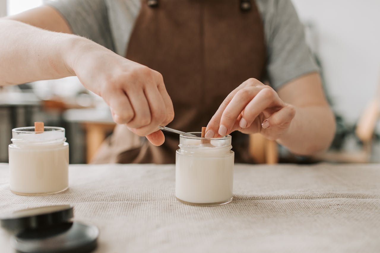 Close-up of artisan crafting handmade candles with wooden wicks in workshop.